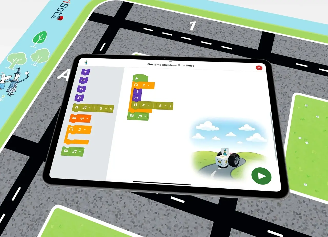 Tablet mit eXperiBot Kids App und der „Wege programmieren“ Spielmatte im Hintergrund.