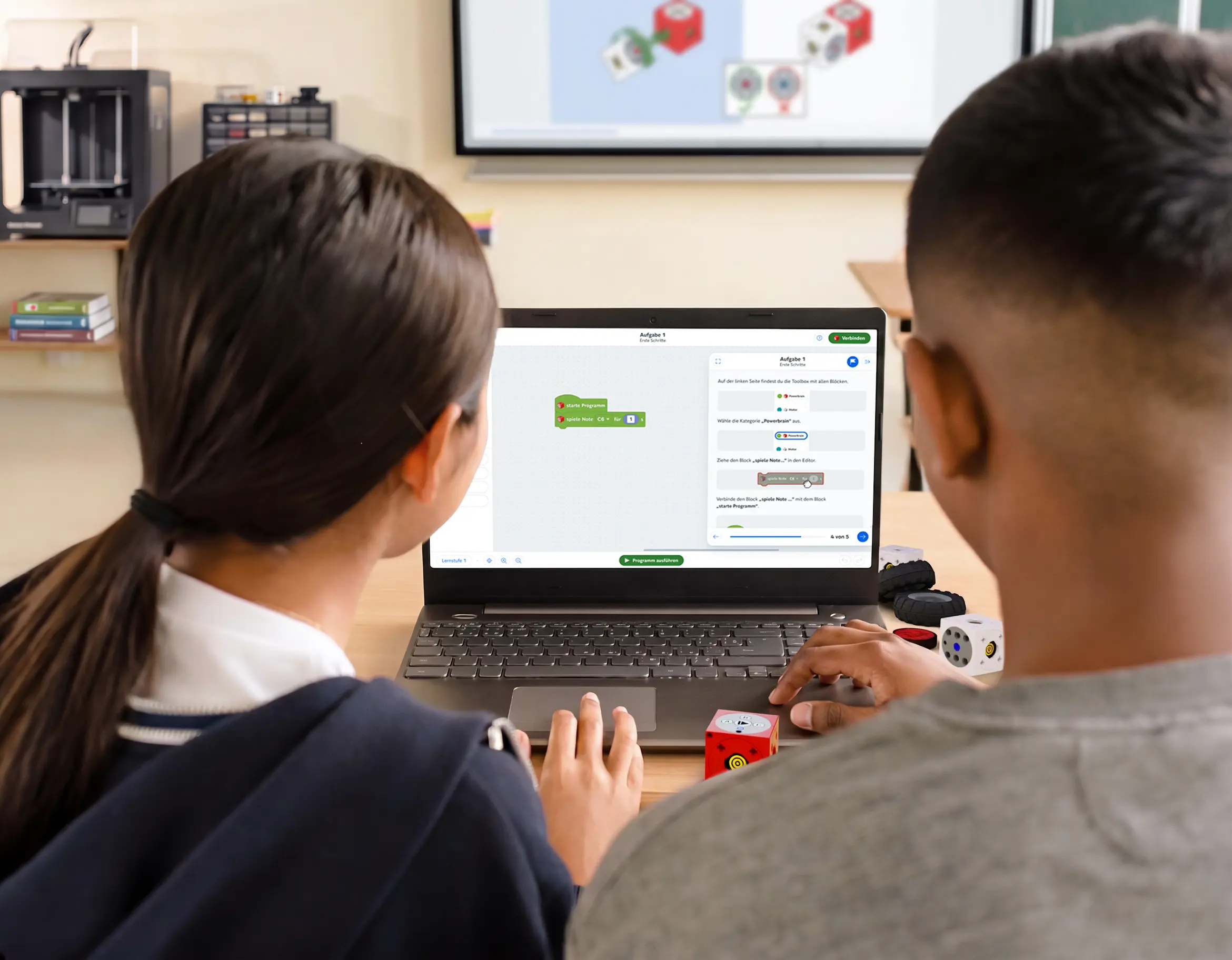 Schülerin und Schüler programmieren eXperiBot mit Laptop.